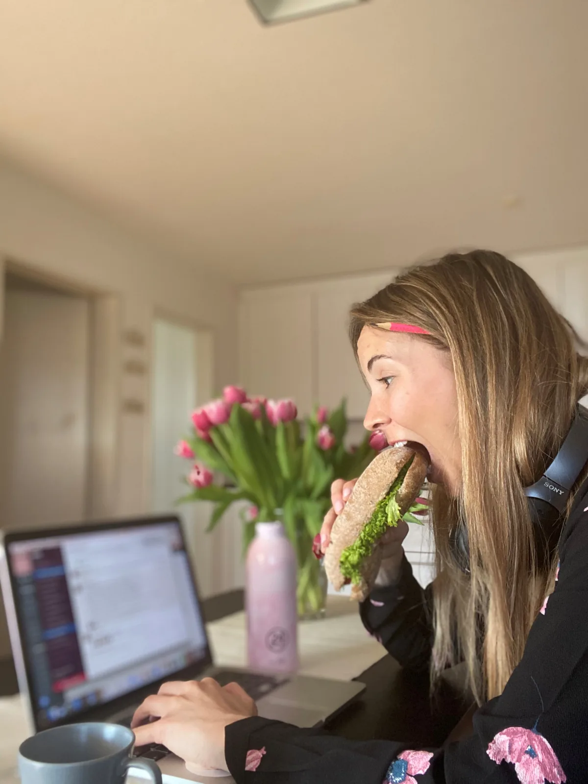 Man sieht Aline Ilk gestresst vor dem Laptop sitzen mit einem Sandwich in der Hand.